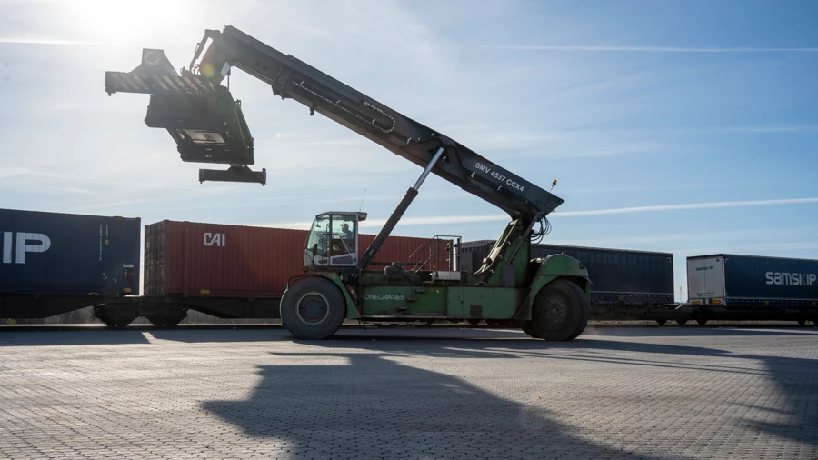 En reachstacker på Nässjö Kombiterminal som lastar av en container från ett godståg.
